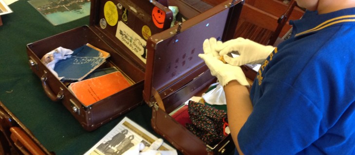 Student with white gloves examines contents of Globite suitcase.
