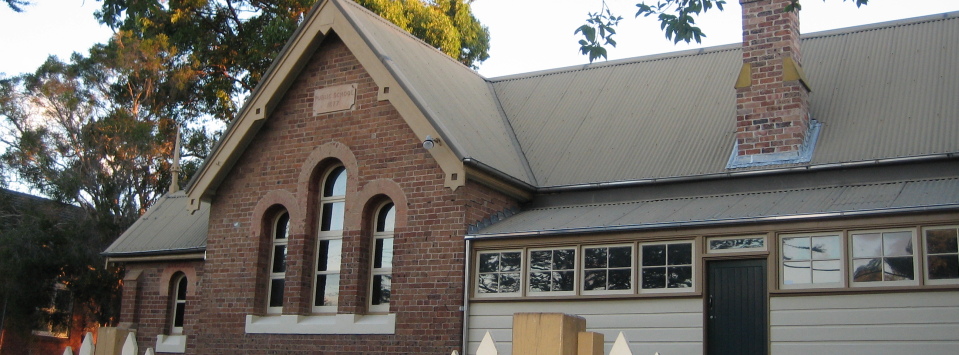 The front view of the Schoolhouse Museum has a church-like appearance with its arches windows, steeply gabled roof and pointed finials.