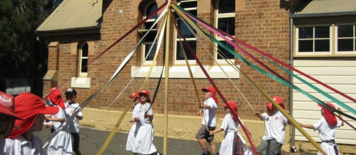 Students skipping around the maypole in front of the NSW Schoolhouse Museum