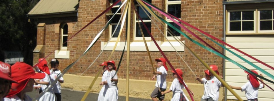 Students skipping around the maypole in front of the NSW Schoolhouse Museum