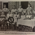 Red Cross workers of Coonamble Superior School with spinning wheel and knitted socks for the war effort. From Education Gazette January 1918